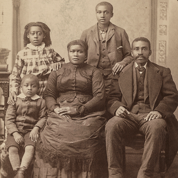 Studio portrait in front of a painted backdrop of Martha and Notley Henderson with their three children. Their son Allen is standing. The Hendersons were early African American settlers in Madison.
